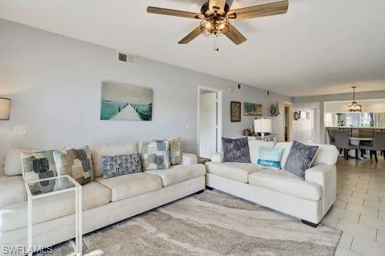Living room featuring a ceiling fan, light-colored walls, and tile flooring