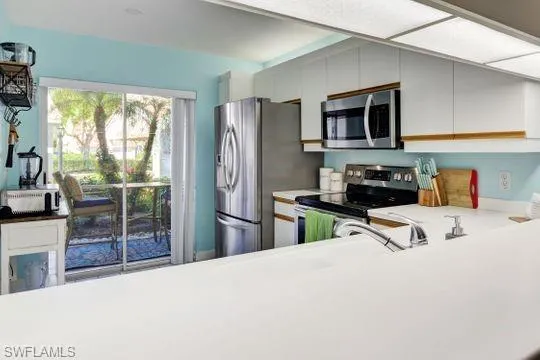 Kitchen featuring white cabinetry, stainless steel appliances, white countertops, and a stainless steel sink with a pull-down faucet