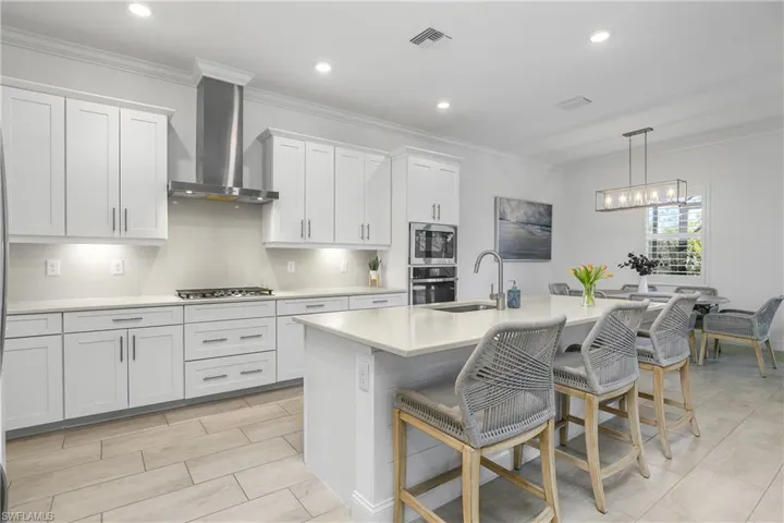 The spacious kitchen is a chef's dream with white cabinetry, stainless steel appliances, a natural gas stove and cooktop, an oversized island and walk-in pantry.