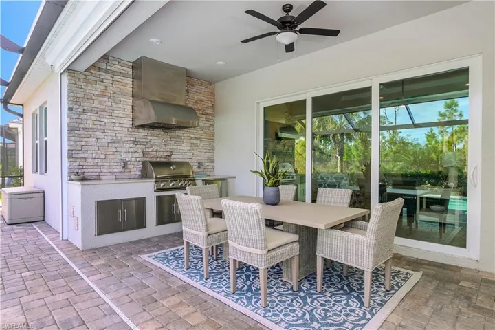 Outdoor living space includes a built-in outdoor kitchen with natural gas grill, beverage cooler, and remote hurricane shades.