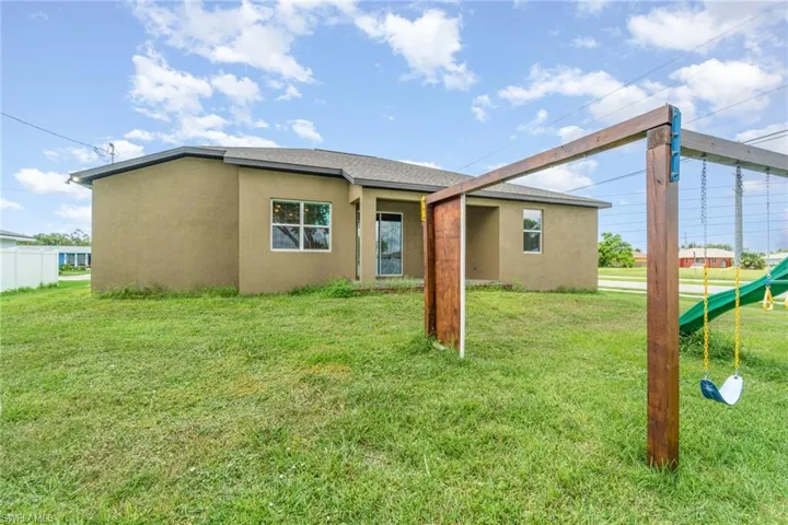 Back of property featuring stucco siding and a lawn
