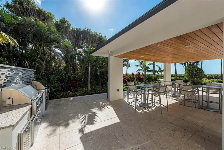 Pool deck featuring exterior kitchen and outdoor, grills and dining space