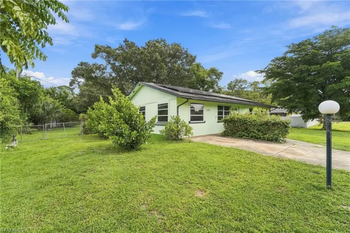 Single-story residence with a light green exterior, multiple windows, and a paved driveway