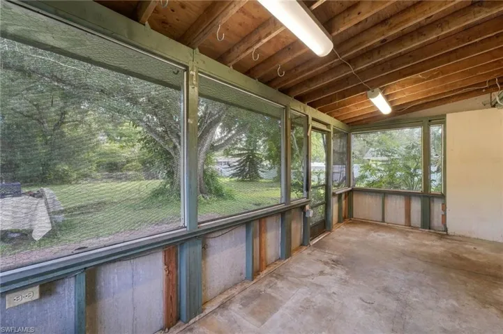 Screened enclosure with exposed wood ceiling beams and concrete flooring