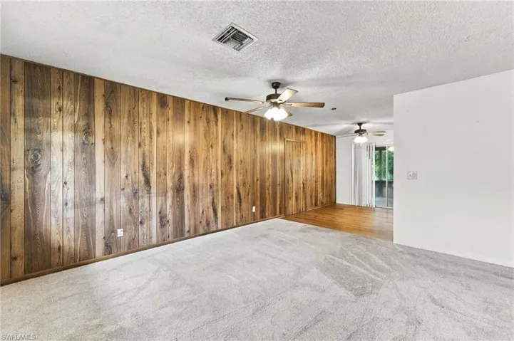 Wood panel wall accent with multiple ceiling fans and light-colored carpeting