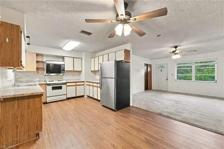 Well-appointed kitchen featuring wood-finish flooring, white cabinetry, and stainless steel appliances