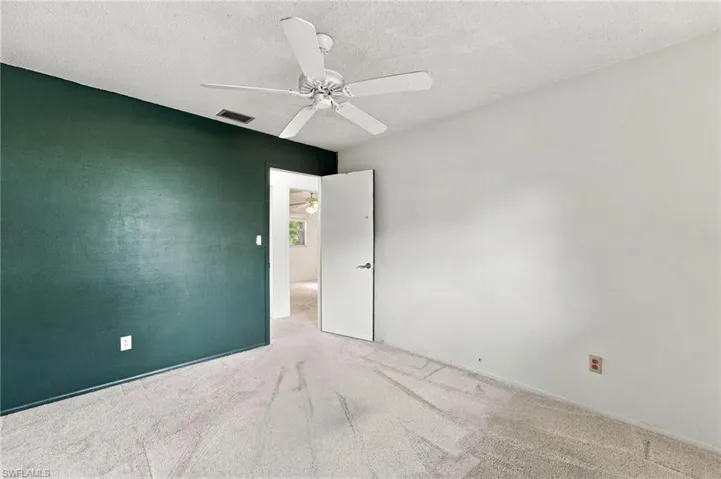 Carpeted flooring, textured walls, and a ceiling fan with integrated lighting