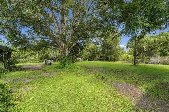 Expansive green space with mature trees and a partial wooden fence