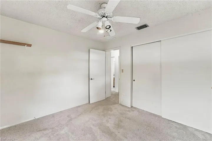 Carpeted flooring, ceiling fan with integrated lighting, sliding closet doors, and interior door