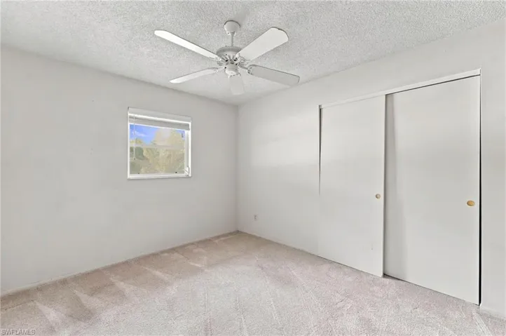 Neutral-toned carpeting, white walls, and a ceiling fan with integrated lighting