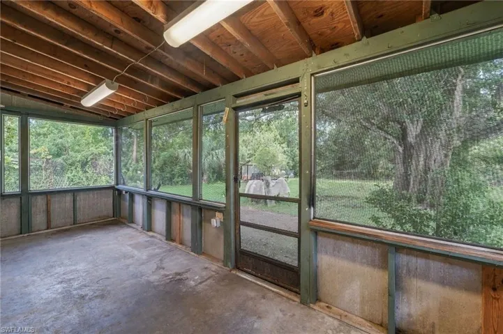 Screened-in porch featuring a concrete floor, exposed wood beam ceiling, and multiple windows