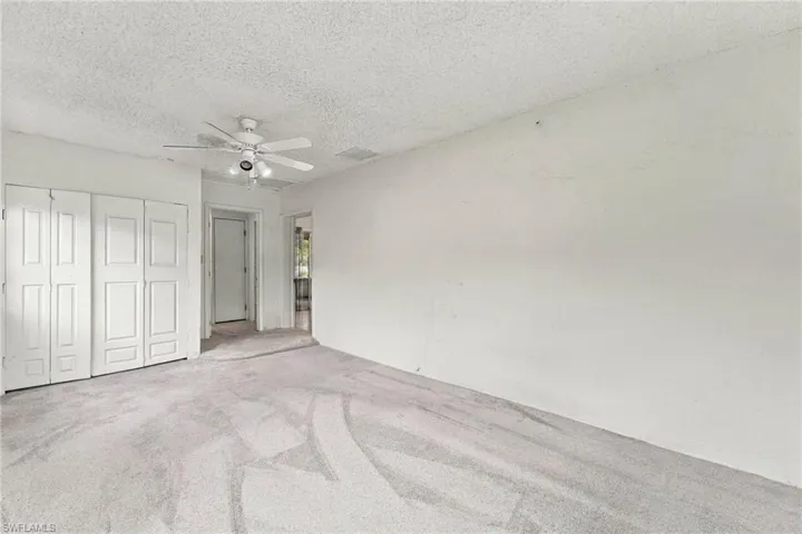 Neutral tone wall finishes, ceiling fan with integrated lighting, and carpet flooring