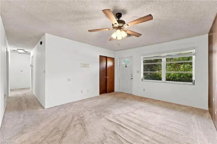 Ceiling fan with integrated lighting, a panel door with decorative glass inserts, and a hallway with flush-mount lighting