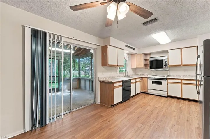 Kitchen featuring wood-finish flooring, two-tone cabinetry, and a full suite of appliances
