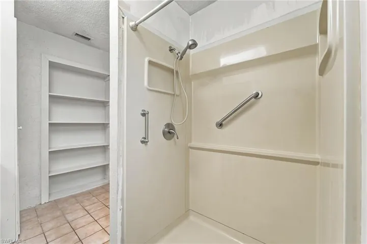 Fiberglass shower stall with grab bars and a handheld showerhead