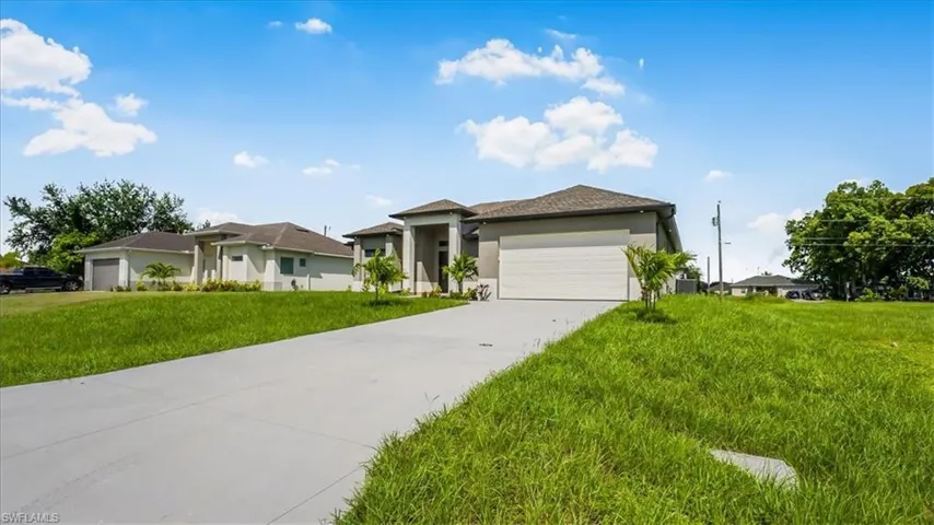 Prairie-style home with a garage, stucco siding, a front lawn, and concrete driveway
