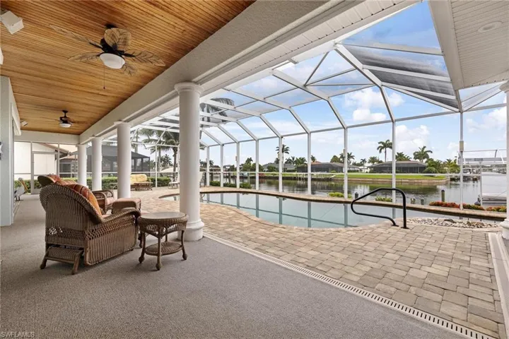 View of swimming pool with a patio area, a water view, a lanai, and ceiling fan