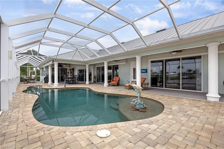 View of pool featuring glass enclosure, a patio area, and ceiling fan