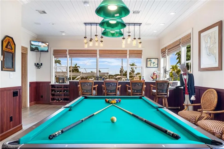 Playroom featuring indoor bar, ornamental molding, pool table, tile patterned flooring, and wood ceiling