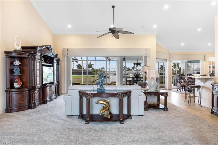 Living room featuring vaulted ceiling, ornamental molding, ceiling fan, and hardwood / wood-style floors