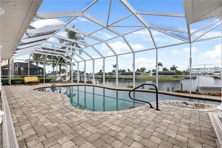View of pool with a patio, a water view, and glass enclosure