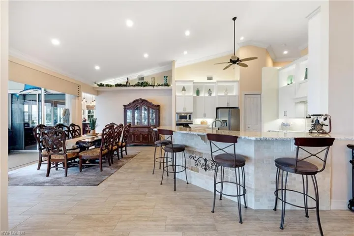 Kitchen featuring crown molding, white cabinets, light stone counters, ceiling fan, and stainless steel appliances