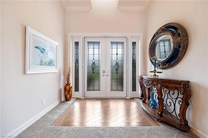Carpeted entryway featuring french doors and ornamental molding