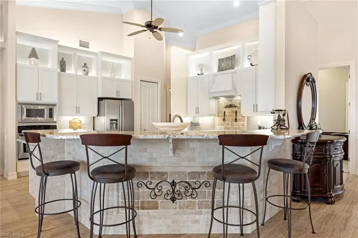 Kitchen with white cabinets, stainless steel appliances, a breakfast bar, and light wood-type flooring