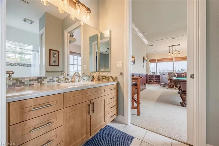Bathroom with vanity, tile patterned floors, tasteful backsplash, and crown molding