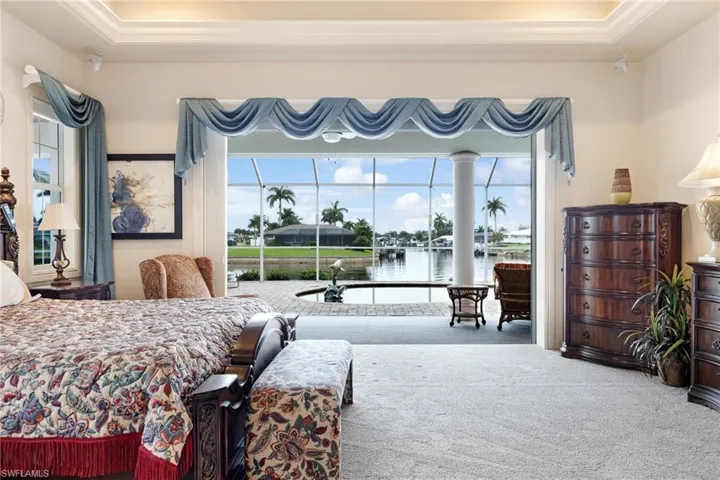 Bedroom with a water view, ornamental molding, carpet floors, and a raised ceiling