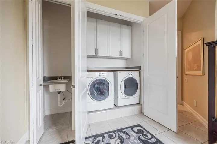 Laundry room with washing machine and dryer, cabinets, and light tile patterned floors