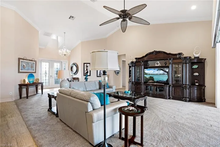 Living room with crown molding, ceiling fan with notable chandelier, and wood-type flooring