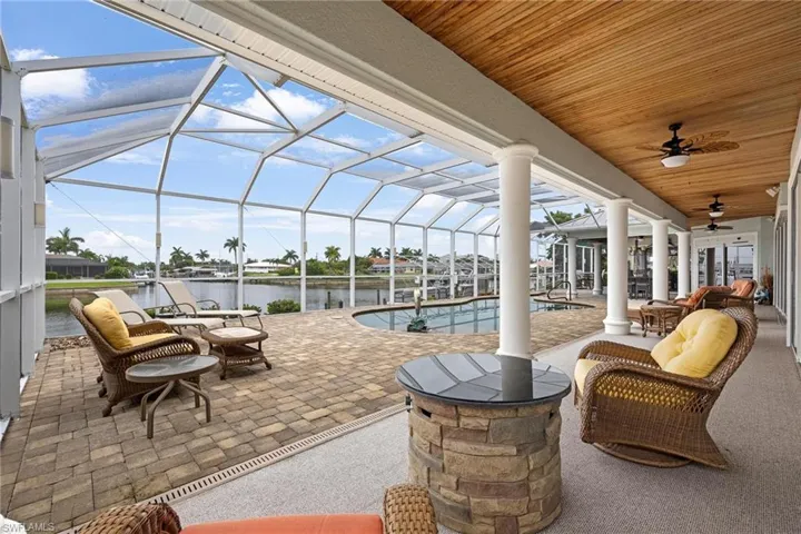 Sunroom featuring decorative columns, a water view, wooden ceiling, and ceiling fan