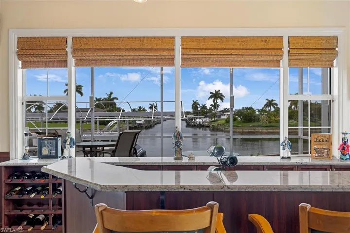Bar featuring a water view, light stone countertops, and a healthy amount of sunlight