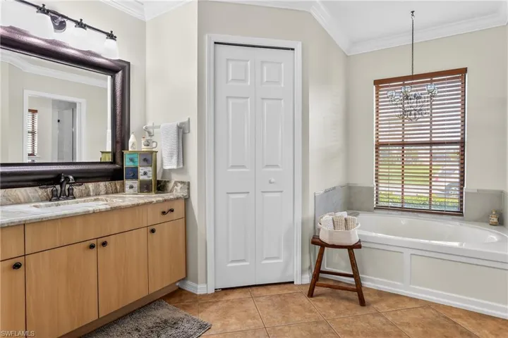Full bath with a closet, crown molding, vanity, a garden tub, and  tile floors