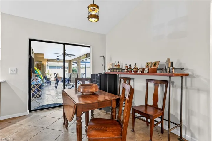 Dining space with vaulted ceiling, light tile patterned flooring, and a ceiling fan