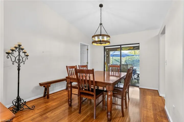 Dining room with laminate floors, vaulted ceiling, and suspended lighting