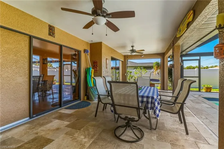 Covered outdoor dining space, ceiling fan, and a travertine deck!