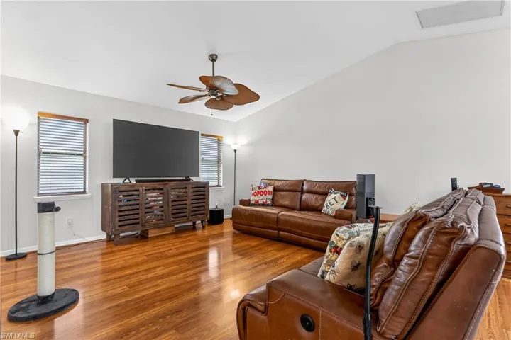 Family room with laminate floors, plenty of natural light, lofted ceiling, and a ceiling fan