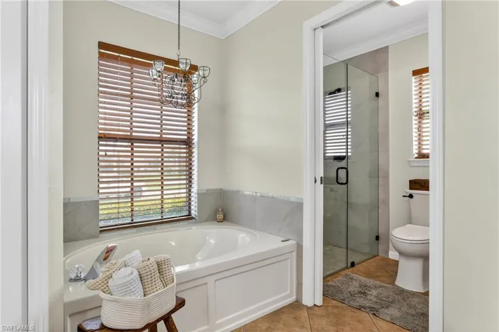 Bathroom featuring crown molding, a garden tub, a tiled shower, and tile  floors