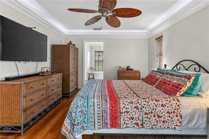 Bedroom featuring crown molding, laminate floors, a ceiling fan, and a tray ceiling