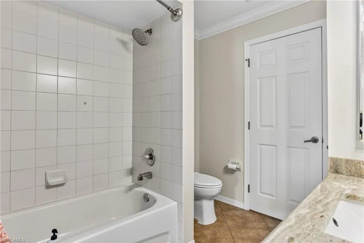 Bathroom featuring crown molding, vanity, tile floors, and bathing tub / shower combination