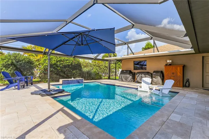 Swimming pool with a travertine deck, picture window screen cage and waterfall!