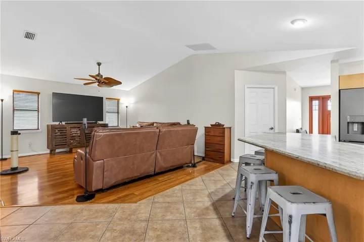 Family room featuring light tile floors, vaulted ceiling, and ceiling fan