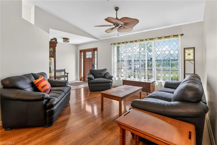 Living room with a ceiling fan, vaulted ceiling, and laminate