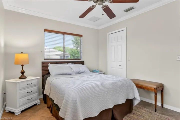 Bedroom featuring crown molding, a closet, a ceiling fan, and laminate floor