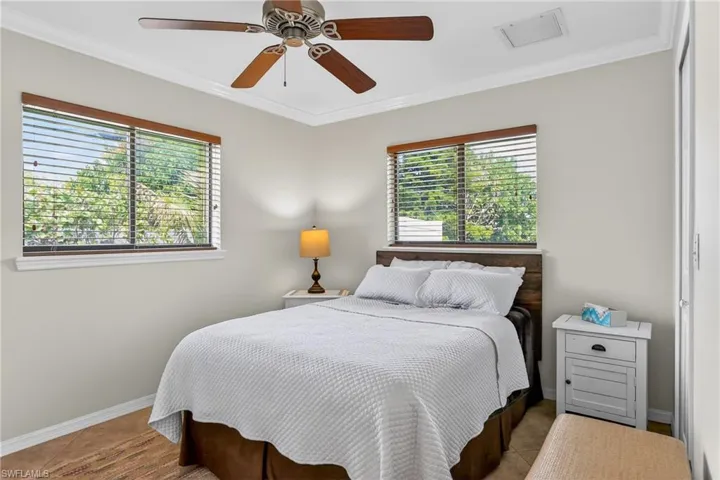 Bedroom featuring crown molding, a ceiling fan, and multiple windows