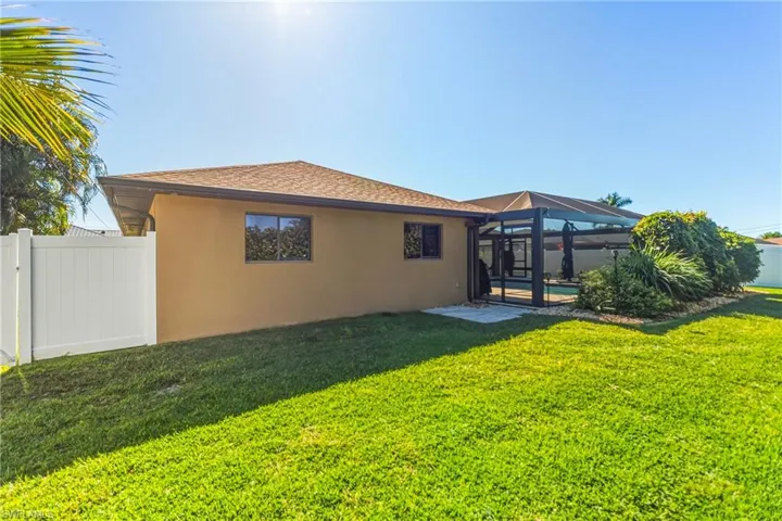 Rear view of house featuring screened pool & deck, a fenced yard, stucco siding, and a shingled roof
