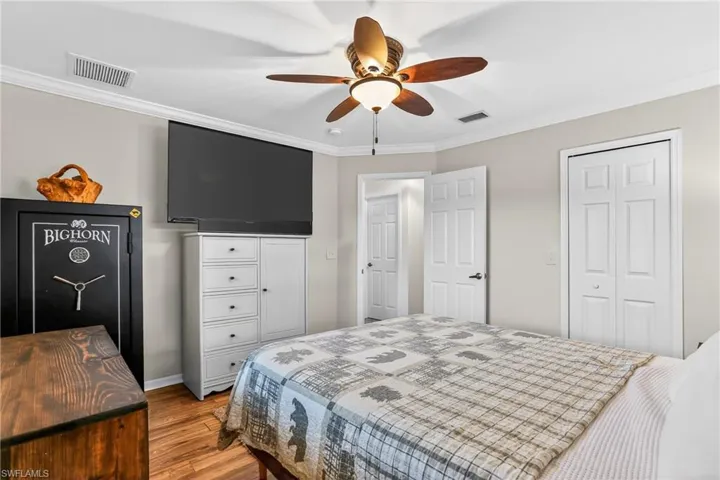 Bedroom with crown molding, laminate floors, a ceiling fan, and a closet