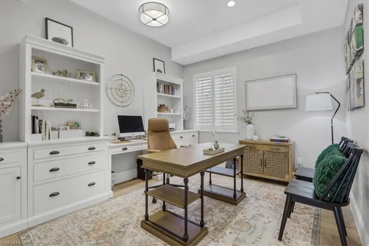 White cabinetry with open shelving and lower drawer storage, tray ceiling, recessed lighting, and window shutters